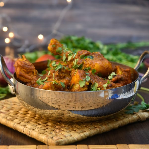 A silver bowl of The Viceroy Royal Indian Dining's chicken curry, garnished with fresh cilantro.